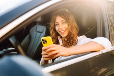 Kadın sürücü arabada akıllı telefon kullanıyormuş. Yönlendirme. Hareket konsepti, modern teknoloji