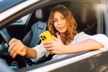 Kadın sürücü arabada akıllı telefon kullanıyormuş. Yönlendirme. Hareket konsepti, modern teknoloji