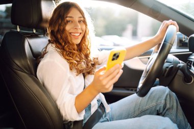 Kadın sürücü arabada akıllı telefon kullanıyormuş. Yönlendirme. Hareket konsepti, modern teknoloji