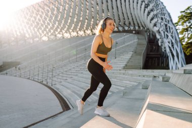 Genç bir kadın açık havada yoga minderinde spor yapıyor. Spor kıyafetleriyle egzersiz yapan sporcu bir kadın. Spor, spor konsepti. Etkin yaşam biçimi.