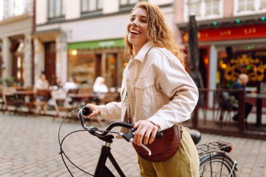 Güneşli bir günde genç bir turist Avrupa sokaklarında bisiklet sürüyor. Şık kıyafetler içindeki güzel bir kadın dışarıda eğleniyor. Yürüme konsepti. Etkin yaşam biçimi.