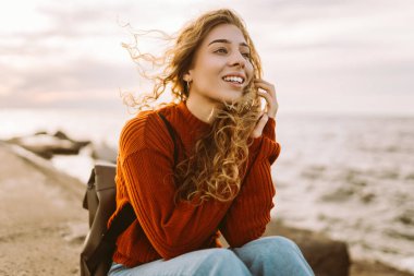 Sırt çantalı hoş bir kadın deniz fenerinde günbatımının tadını çıkarıyor, özgürlüğü hissediyor. Turist doğada dinleniyor, sette yürüyor. Yürüme, seyahat, özgürlük kavramı. Yaşam biçimi.