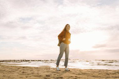Sırt çantalı hoş bir kadın deniz fenerinde günbatımının tadını çıkarıyor, özgürlüğü hissediyor. Turist doğada dinleniyor, sette yürüyor. Yürüme, seyahat, özgürlük kavramı. Yaşam biçimi.