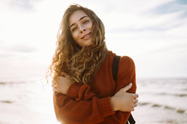 Sırt çantalı hoş bir kadın deniz fenerinde günbatımının tadını çıkarıyor, özgürlüğü hissediyor. Turist doğada dinleniyor, sette yürüyor. Yürüme, seyahat, özgürlük kavramı. Yaşam biçimi.