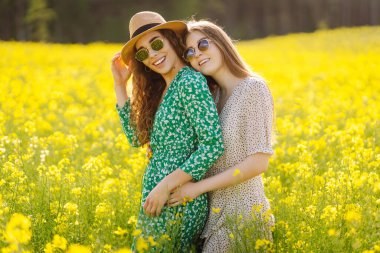Çiçek açan bir kolza tohumu tarlasında birlikte yürüyen iki genç bayan arkadaş. Güzel kadınlar birlikte vakit geçirir, açık havada güneşli havanın tadını çıkarırlar. Rahatlama, yürüyüş, özgürlük kavramı.