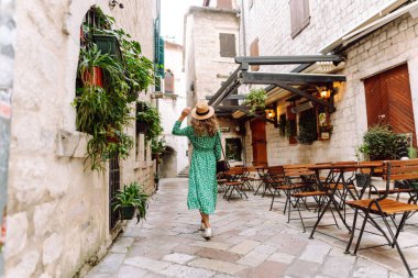 Yeşil elbiseli mutlu bir turist Avrupa 'nın eski sokaklarında gezinin tadını çıkarıyor. Güzel bir kadın eğleniyor. Turizm, tatil kavramı.