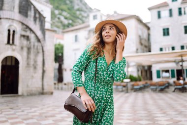 Yeşil elbiseli mutlu bir turist Avrupa 'nın eski sokaklarında gezinin tadını çıkarıyor. Güzel bir kadın eğleniyor. Turizm, tatil kavramı.