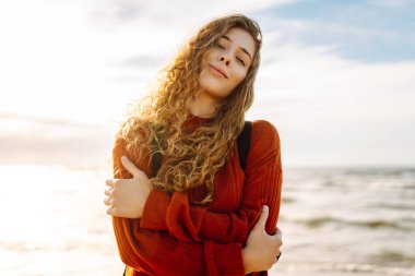 Güneşli sahilde rüzgarın tadını çıkaran rahat kadın portresi. Güzel bir kadın denizin yanında özgürlüğünü hisseder. Keyif, rahatlama, özgürlük kavramı.