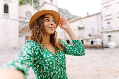 Şirin turist güzel mimari binaların arka planında selfie çekiyor. Genç bir kadın yeni Avrupa caddelerinde yürümekten hoşlanıyor. Selfie, blog ve turizm konsepti.