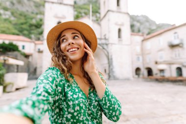 Şirin turist güzel mimari binaların arka planında selfie çekiyor. Genç bir kadın yeni Avrupa caddelerinde yürümekten hoşlanıyor. Selfie, blog ve turizm konsepti.