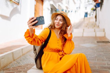 Neşeli kadın eski şehirde yürürken telefonla selfie çekiyor. Genç bir turist dağ manzarasının tadını çıkarıyor, telefonda her şeyi çekiyor. Turizm, hafta sonu konsepti.