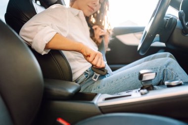 Sürücü koltuğundaki kadının emniyet kemerini takıp emniyet kemerini taktığı bir fotoğraf. Arabadaki genç bayan sürücü güvenliğini gözetliyor. Sürüş, güvenlik kavramı.