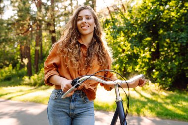 Genç modern kadın parkta bisiklet sürüyor. Spor aktiviteleri. Çevreyle ilgilenmek