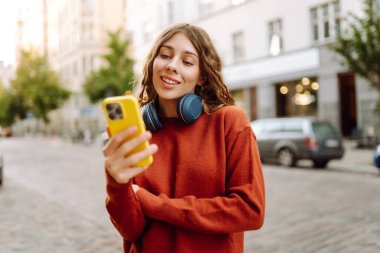 Sokakta yürürken müzik dinleyen genç bir kadın. Seyahat, turizm, teknoloji, blog konsepti