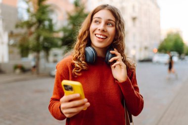 Sokakta yürürken müzik dinleyen genç bir kadın. Seyahat, turizm, teknoloji, blog konsepti