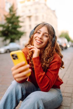 Sokakta yürürken müzik dinleyen genç bir kadın. Seyahat, turizm, teknoloji, blog konsepti