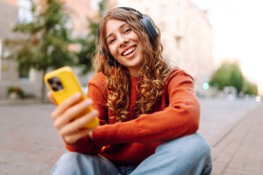 Sokakta yürürken müzik dinleyen genç bir kadın. Seyahat, turizm, teknoloji, blog konsepti