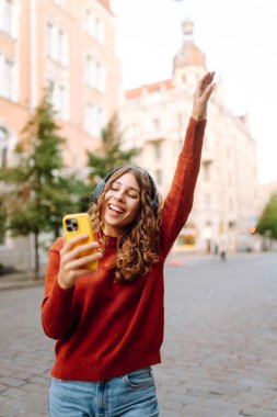 Sokakta yürürken müzik dinleyen genç bir kadın. Seyahat, turizm, teknoloji, blog konsepti