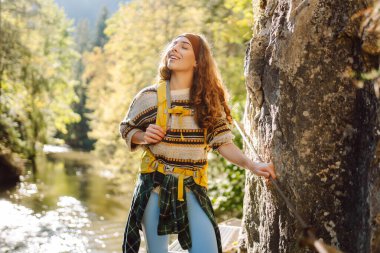Kadın turist yazın doğayı keşfediyor, köprüde yürüyor. Ormanlarda dolaşan büyük sırt çantalı bir yürüyüşçü. Etkin yaşam biçimi
