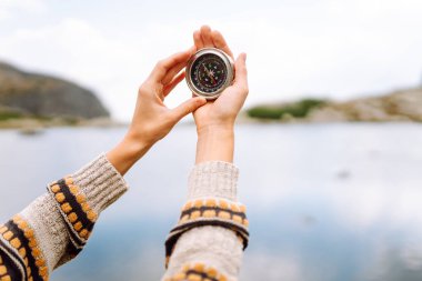 Bir dağ yolunun arka planında kadın turistin elinde pusula var. Seyahat ve yürüyüş için bir yol seçiyorum. Etkin yaşam biçimi.