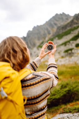 Bir dağ yolunun arka planında kadın turistin elinde pusula var. Seyahat ve yürüyüş için bir yol seçiyorum. Etkin yaşam biçimi.