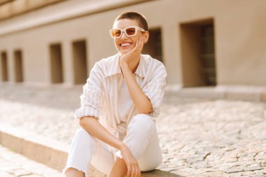 Sokak merdivenlerinde oturan kısa saçlı güzel bir kadının portresi. Moda tarzı. Şehir hayatı.