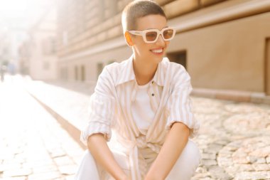 Sokak merdivenlerinde oturan kısa saçlı güzel bir kadının portresi. Moda tarzı. Şehir hayatı.