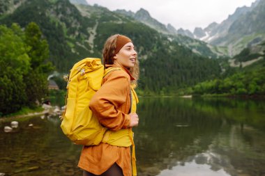Sırt çantalı genç bir kadın dağda yürüyüş yapıyor. Seyahat, macera. Etkin bir yaşam biçimi kavramı