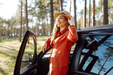 Arabanın yanında güzel bir kadın var ve doğal hayatın tadını çıkarıyor. Şebeke dışı tatil kavramı, ağaçlar ve odunlarla gezmek. İnsanlar araçla dışarıda boş vakit geçirmekten hoşlanıyor.