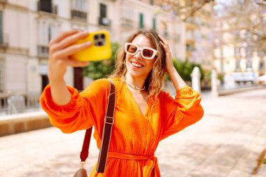 Güzel bir kadın selfie çeker, güzel caddelerde yürür. Bloglama, arkadaşlarla iletişim, seyahat kavramı