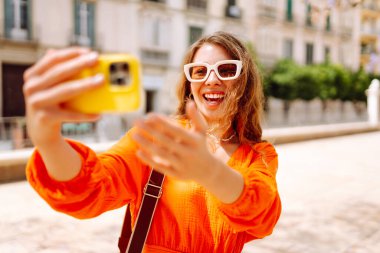 Güzel bir kadın selfie çeker, güzel caddelerde yürür. Bloglama, arkadaşlarla iletişim, seyahat kavramı