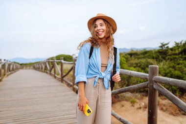 Mutlu kadın akıllı telefon kullanıyor ve deniz kenarında güneşli bir gezinti güvertesinde gülümsüyor. Boş zaman, açık hava ve doğaya yakın. Avrupa seyahati