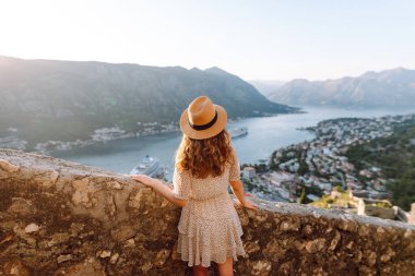 Turist kadının arka görüntüsü körfeze ve şehre bir gözlem güvertesinden bakıyor. Avrupa seyahati. Yaşam tarzı, tatil, turizm, doğa, aktif yaşam