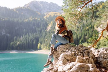 Yüksek bir dağ gölünde sırt çantasıyla gezen kadın gezginin arka görüntüsü. Seyahat, doğa konsepti.