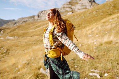 Dişi turist, sırt çantasıyla dağlarda dikilip manzarayı seyrediyor. Yürüyüş. Avrupa seyahati