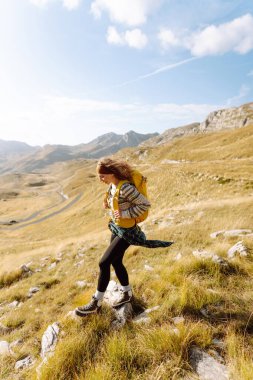 Dişi turist, sırt çantasıyla dağlarda dikilip manzarayı seyrediyor. Yürüyüş. Avrupa seyahati