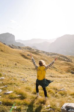 Dişi turist, sırt çantasıyla dağlarda dikilip manzarayı seyrediyor. Yürüyüş. Avrupa seyahati