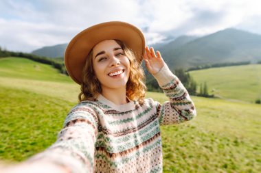 Genç güzel yürüyüşçü kadın dağın tepesinde selfie portresi çekiyor. Yürürken ve tırmanırken. Teknoloji, seyahat, blog konsepti