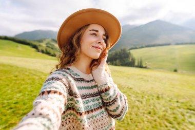 Genç güzel yürüyüşçü kadın dağın tepesinde selfie portresi çekiyor. Yürürken ve tırmanırken. Teknoloji, seyahat, blog konsepti