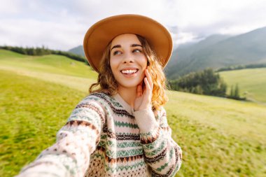 Genç güzel yürüyüşçü kadın dağın tepesinde selfie portresi çekiyor. Yürürken ve tırmanırken. Teknoloji, seyahat, blog konsepti