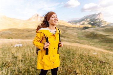 Kadın turist, sırt çantasıyla dağlarda durmuş manzarayı seyrediyor. Ulusal Park 'ta vahşi doğayı keşfediyorum. Seyahat, yürüyüş konsepti