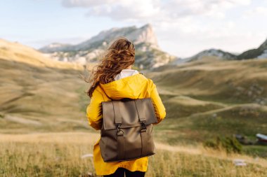 Kadın turist, sırt çantasıyla dağlarda durmuş manzarayı seyrediyor. Ulusal Park 'ta vahşi doğayı keşfediyorum. Seyahat, yürüyüş konsepti