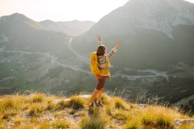 Kadın turist yaz güneşli bir günde dağın tepesinde güneş ışığı altında yürüyor. Güzel dağlar manzara. Macera aktif