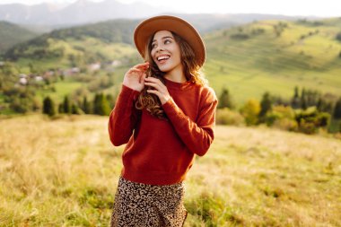 Yeşil çimlerde eğlenen gülümseyen bir kadının portresi. Güneşli havanın tadını çıkaran şapkalı güzel bir gezgin. Güzellik kavramı, rahatlama, özgürlük..