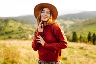 Yeşil çimlerde eğlenen gülümseyen bir kadının portresi. Güneşli havanın tadını çıkaran şapkalı güzel bir gezgin. Güzellik kavramı, rahatlama, özgürlük..