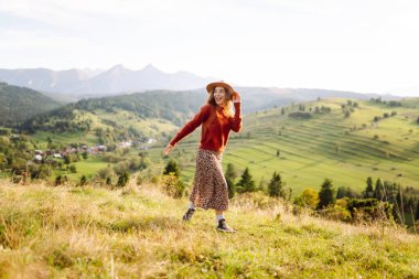 Yeşil çimlerde eğlenen gülümseyen bir kadının portresi. Güneşli havanın tadını çıkaran şapkalı güzel bir gezgin. Güzellik kavramı, rahatlama, özgürlük..