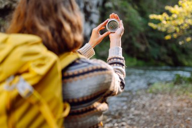 Genç bir kadın yürüyüşçü pusulayla yön arıyor. Yürüyüş yapan bir kadın yürüyüşçünün arka görüntüsü. Navigasyon konsepti, yürüyüş. Etkin yaşam biçimi.