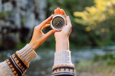 Genç bir kadın yürüyüşçü pusulayla yön arıyor. Yürüyüş yapan bir kadın yürüyüşçünün arka görüntüsü. Navigasyon konsepti, yürüyüş. Etkin yaşam biçimi.