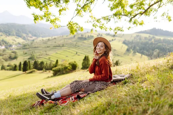 Şapkalı güzel kadın gün batımında Yeşil Tepe 'den manzaranın tadını çıkarıyor. Genç bayan gezgin rahatlar ve manzara karşısında özgürlüğünü hisseder. Seyahat, eğlence, yürüyüş konsepti.
