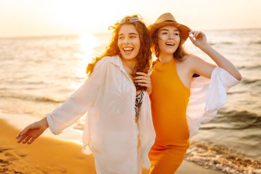 İki genç bayan arkadaş gün batımı kumsalında eğleniyor, birlikte vakit geçiriyorlar. Güzel kadınlar denizde sıcak bir günbatımının tadını çıkarıyorlar. Arkadaşlık, rahatlama konsepti..